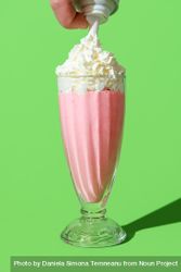Strawberry milkshake topped with whipped cream, minimalist on a green background 4ZzLy4