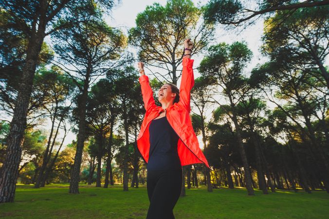 Excited sportswoman with arms raised in park