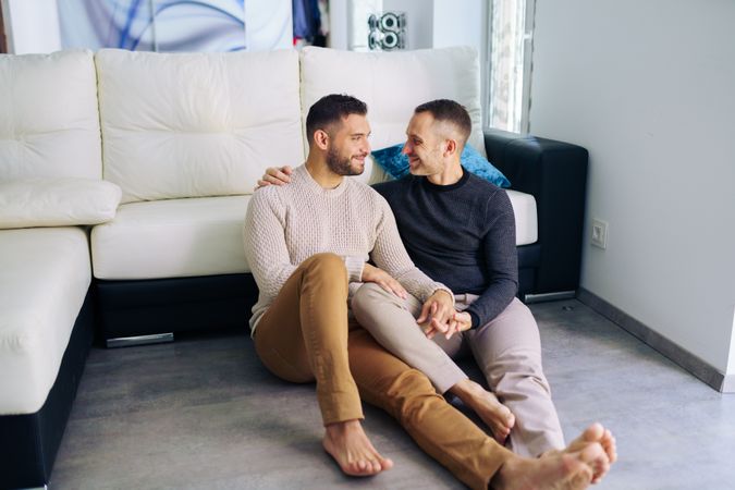 Cute male couple relaxing on floor at home