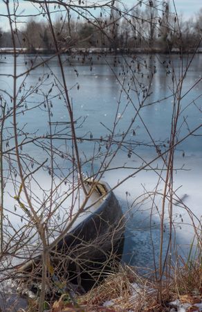Boat on frozen lake pictured through branches
