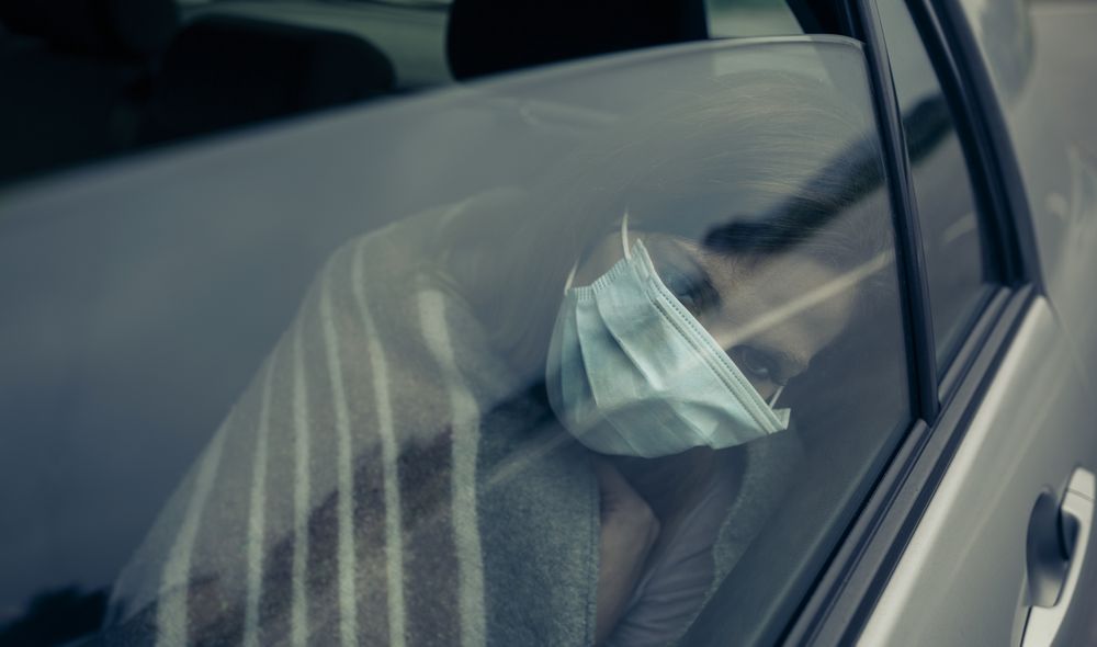View through the car window of a woman with mask