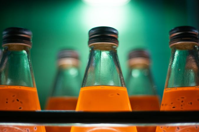 Orange juice bottles in glass backlit in green