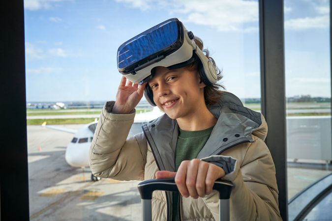 Content child adjusting VR headset and smiling at camera in airp