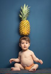 Happy baby holding a pineapple over her head