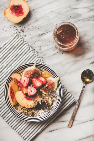 Flat-lay of yogurt bowl with fruit, honey and spoon