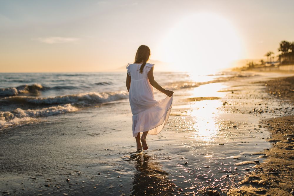 Adorable girl walking on seaside at sunset