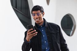 Stylish happy hispanic man with smartphone on street