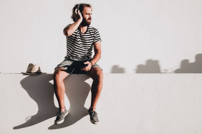 Young male sitting with smartphone and headphones