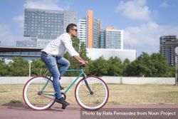 Male riding red and green bike outside next to city buildings on sunny day bY3o15