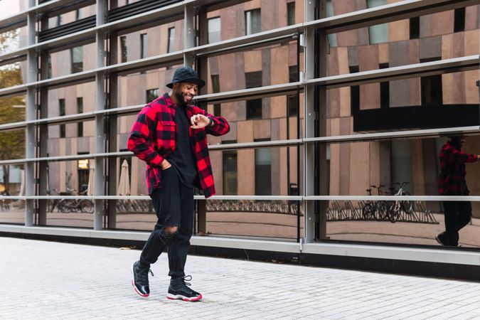 Stylish hurrying Black man walking near modern building
