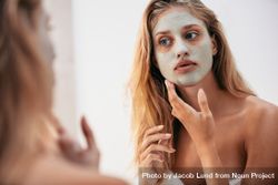 Woman looking in the mirror with mask on her face 5oW2G5