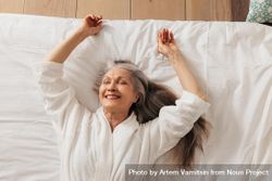 Grey haired woman relaxing on bed smiling with eyes closed 5aQRK5