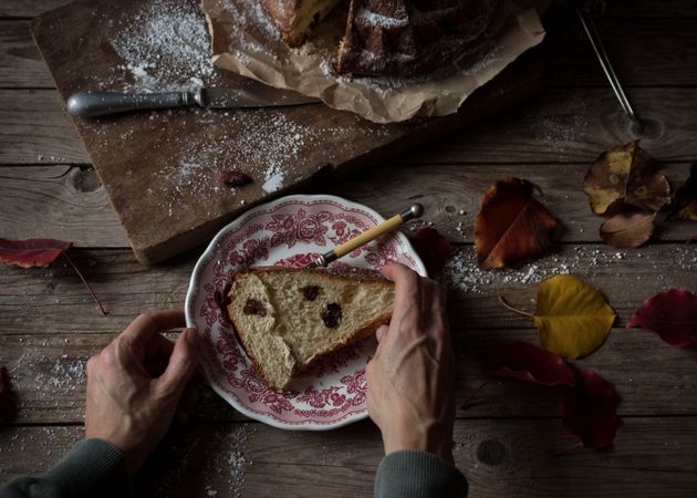 Crop hands holding piece of Kugelhopf near autumn leaves