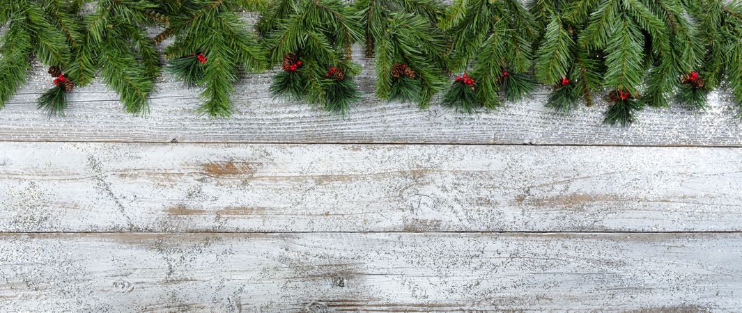 Christmas or New Year holiday background on aged wood with evergreen and red berries
