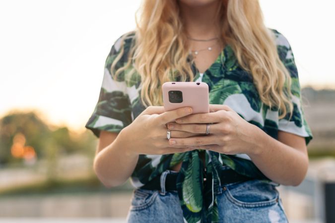 Unrecognizable blonde woman using smartphone outdoors