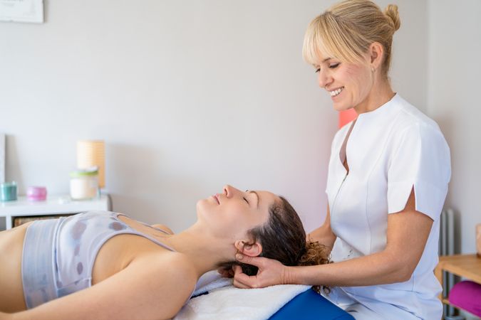 Osteopath working on neck of patient lying down