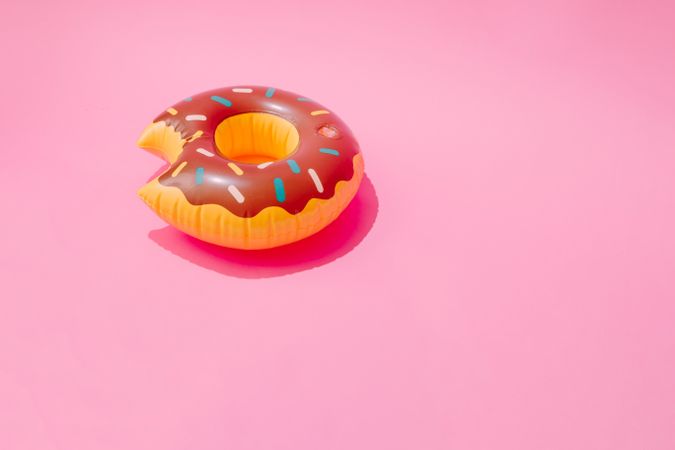Inflatable doughnut pool toy on pastel pink background