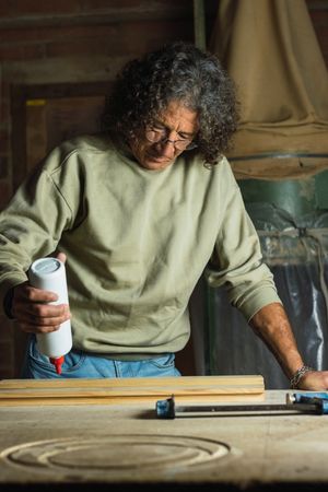 Carpenter gluing wooden board in workshop