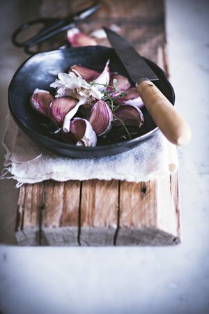 Garlic cloves in peel in bowl with knife