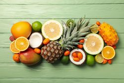 Set of tropical fruit on green wooden background, top view