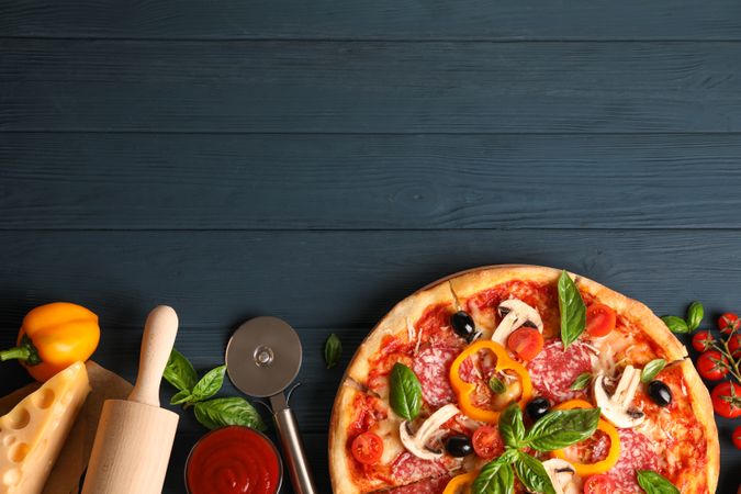 Delicious pizza and ingredients on wooden background, copy space