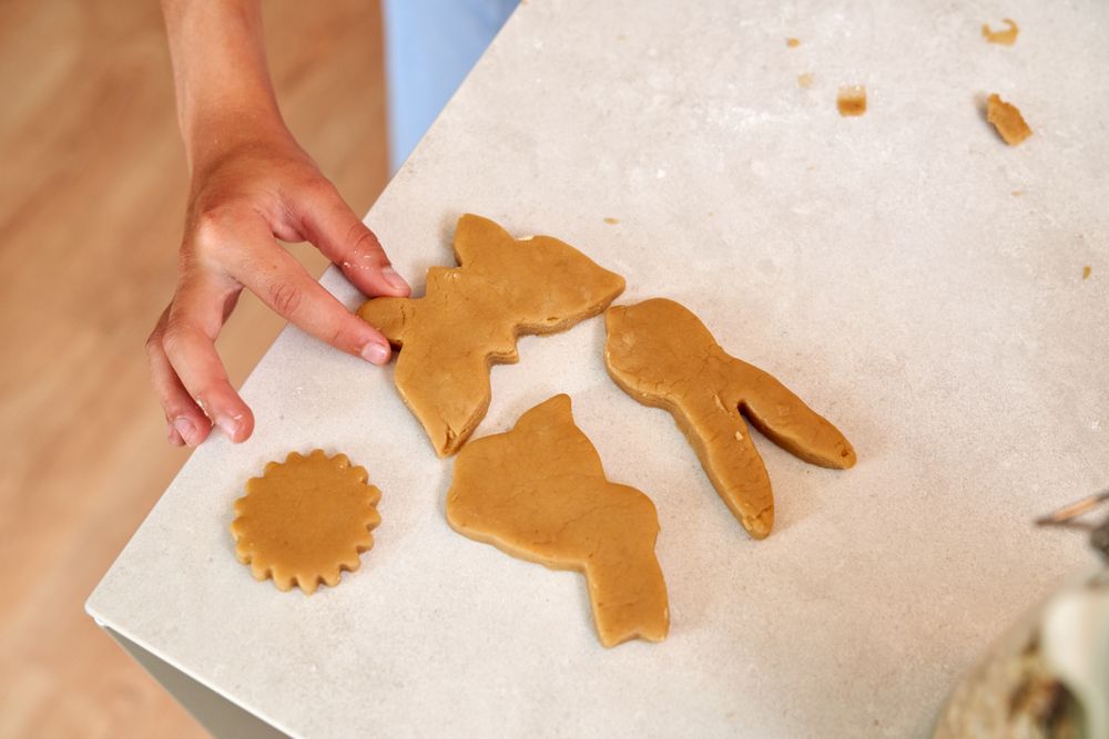 Crop person touching raw cookies on table