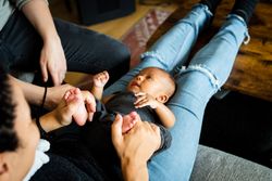 Cute new born baby in mother’s lap as she wears jeans
