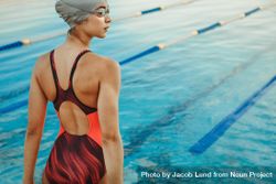 Woman in swimsuit, swim cap and goggles near swimming pool 0WVrpb