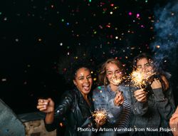 Multi-ethnic group of fun women at a party with confetti and sparklers 4Av7Yb