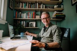 Mature smiling man working in comfortable home office with coffee cup
