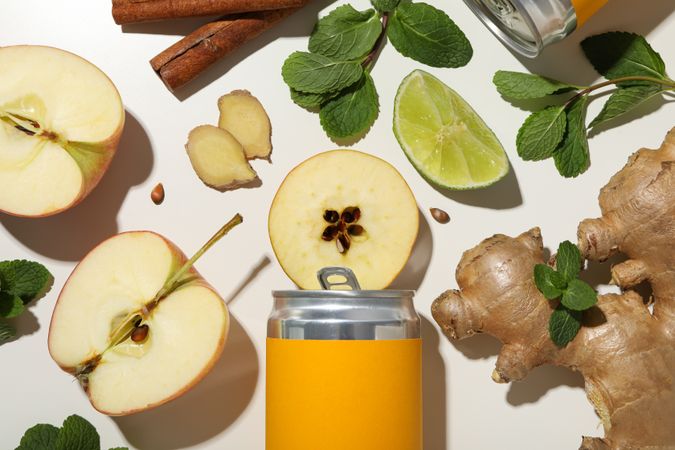 Tin cans, ginger root, pieces of apple, mint and lime on plain background, top view