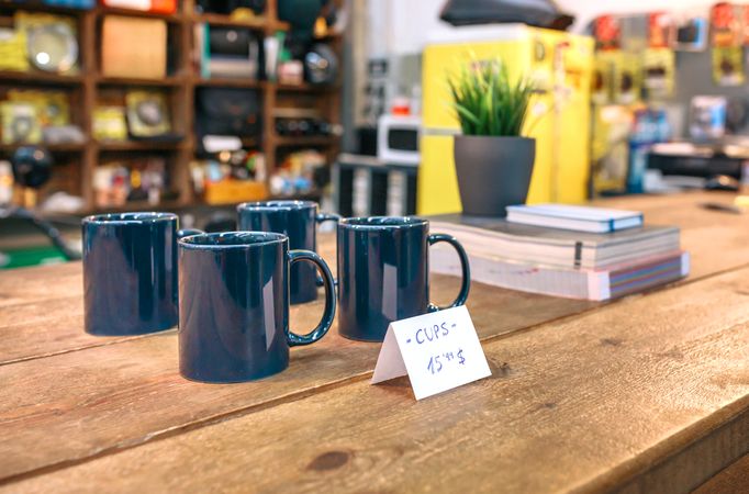 Close up of breakfast blue mugs over wooden counter in local store with industrial style decoration