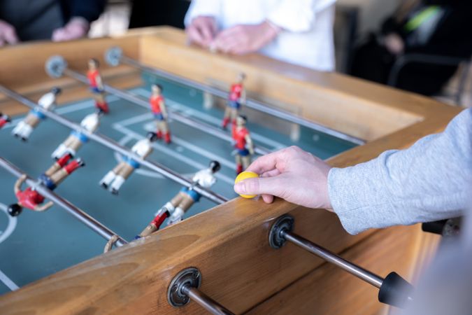 A young man is holding a table football ball before starting the game