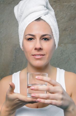 Smiling woman holding glass of water in her hands