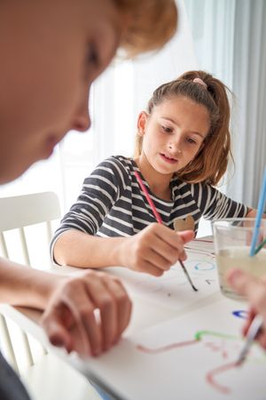 Focused girl painting near boy