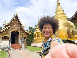 Exuberant traveler shares a moment with a smartphone selfie at golden temple, vacation activities and adventure concept