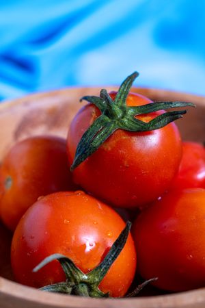 A bunch of red tomatoes are on a wooden table