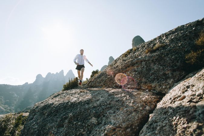 Male running on a rocky terrain with sunflare