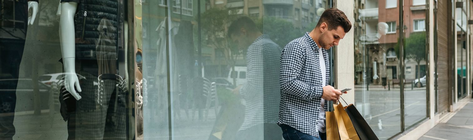 Young man with shopping bags and mobile