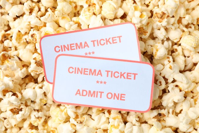 Cinema tickets on popcorn background, close up