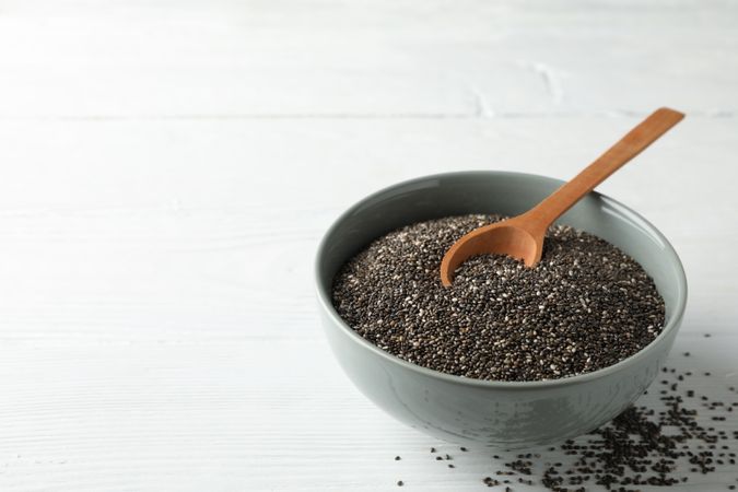 Chia seeds, wood spoon and bowl on wooden background, copy space
