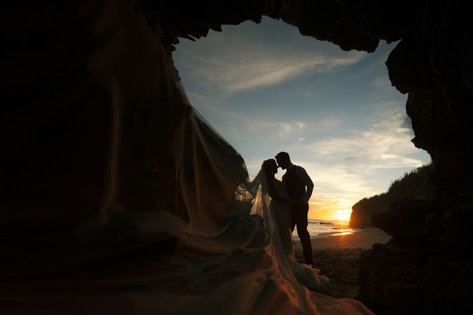 Woman and man embracing in cave on seashore in darkness