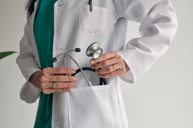 Crop physician in medical robe with stethoscope
