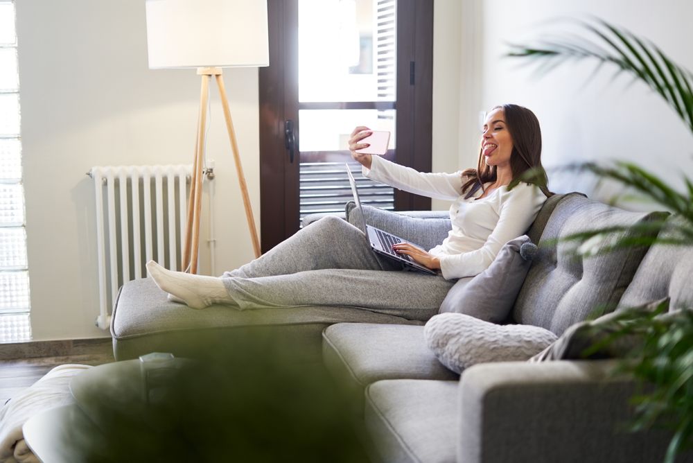 Smiling woman browsing on laptop and sitting on settee