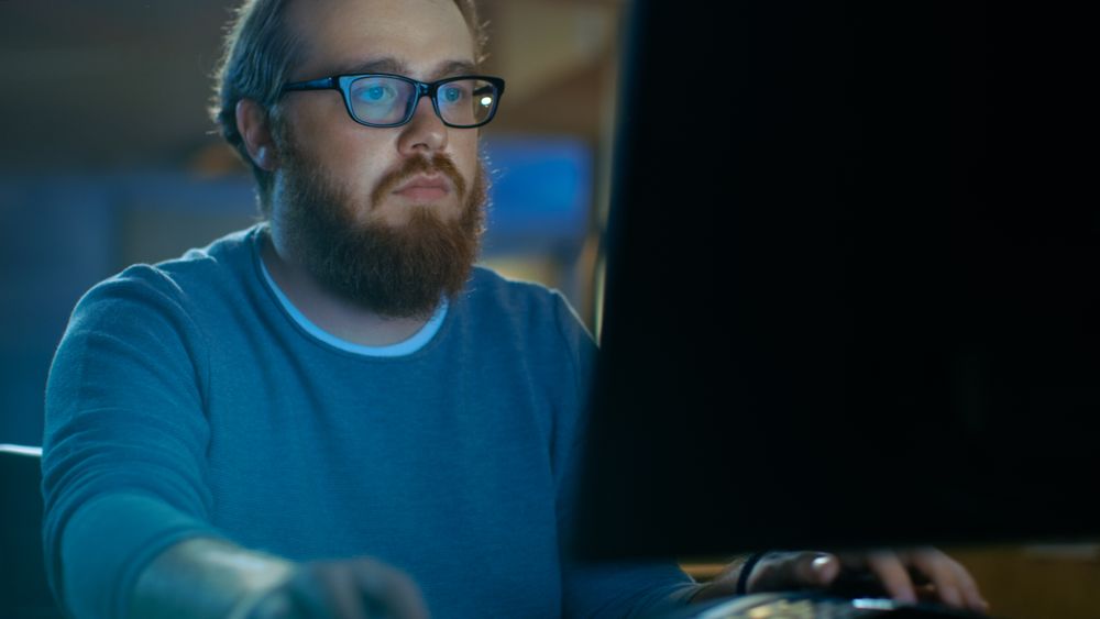 Focused Young Man Works on a Personal Computer.