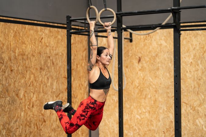 Strong female athlete swinging on rings in a gym