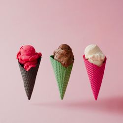 Strawberry, chocolate, and vanilla ice cream in different waffle cones on pink background