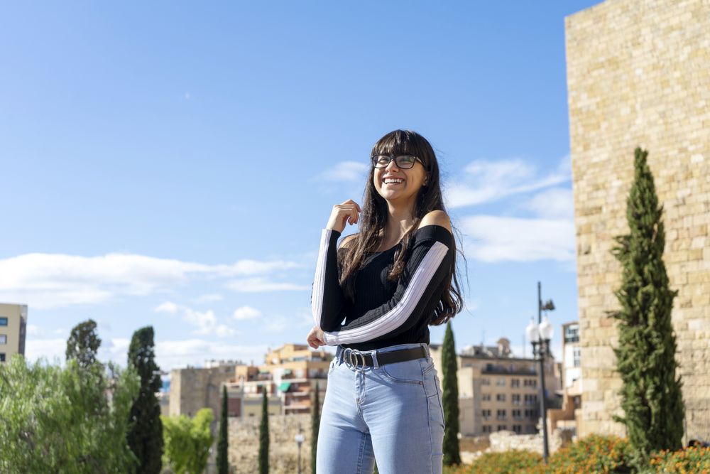 Portrait of beautiful young woman smiling while looking at camera standing in the street