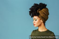 Studio shoot of Black woman with her eyes closed wearing a green hair scarf 4OB675