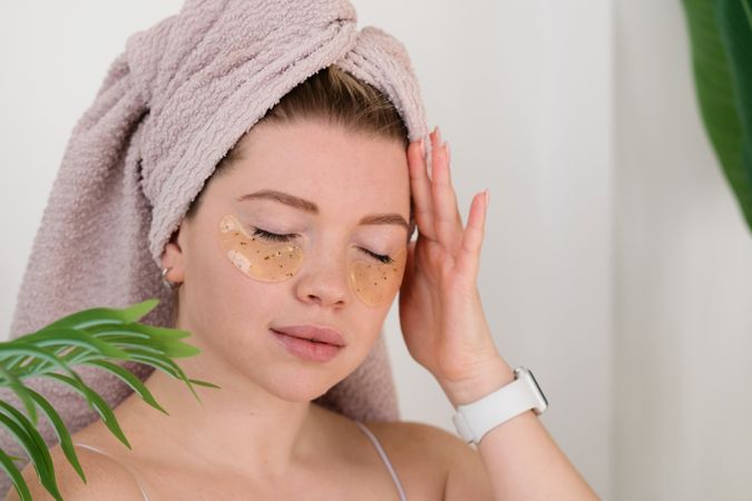 Applying eye patches in skincare routine.